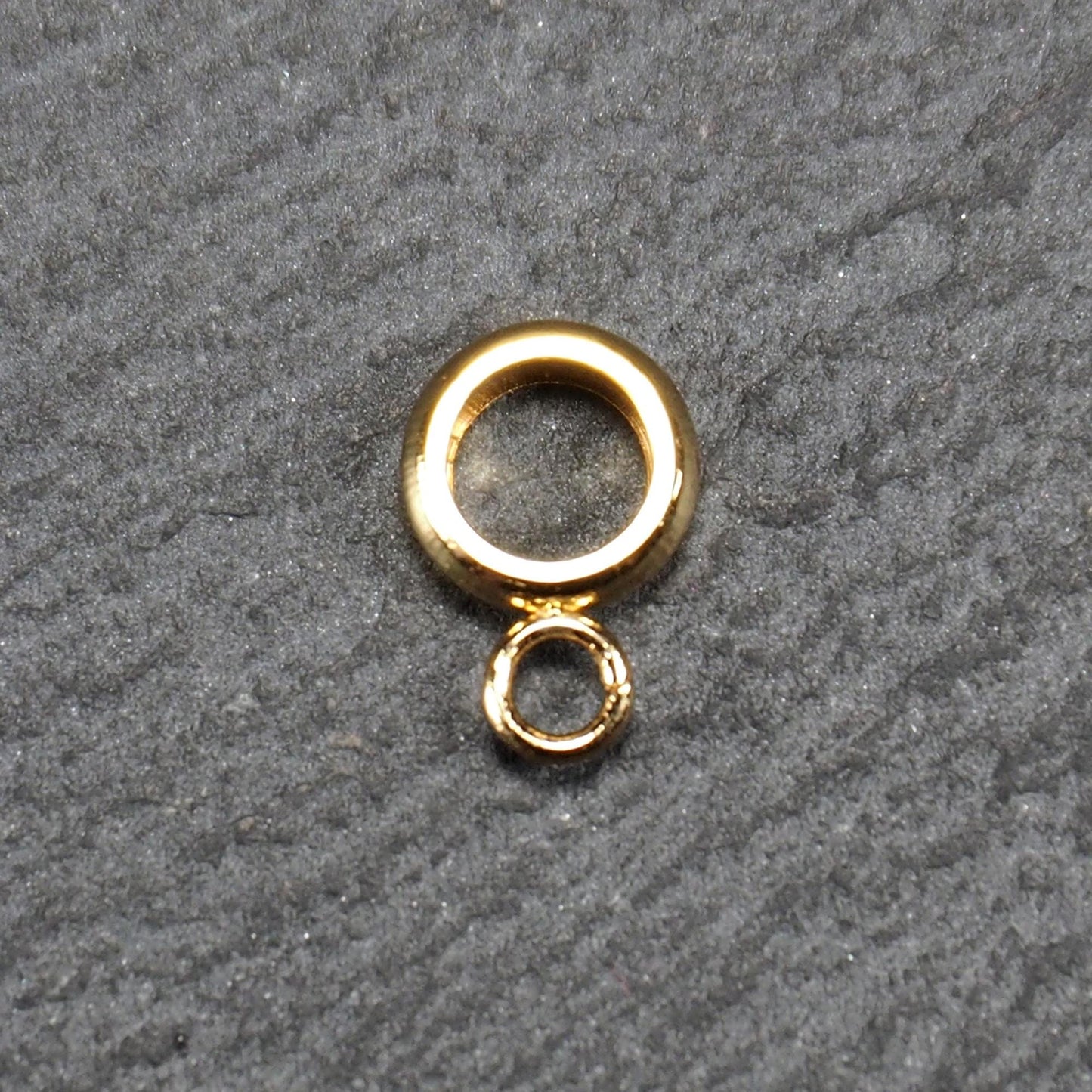 Ringförmige, glänzend goldfarbene Anhängeröse mit großem runden Loch und kleiner runder Anhängerschlaufe.
