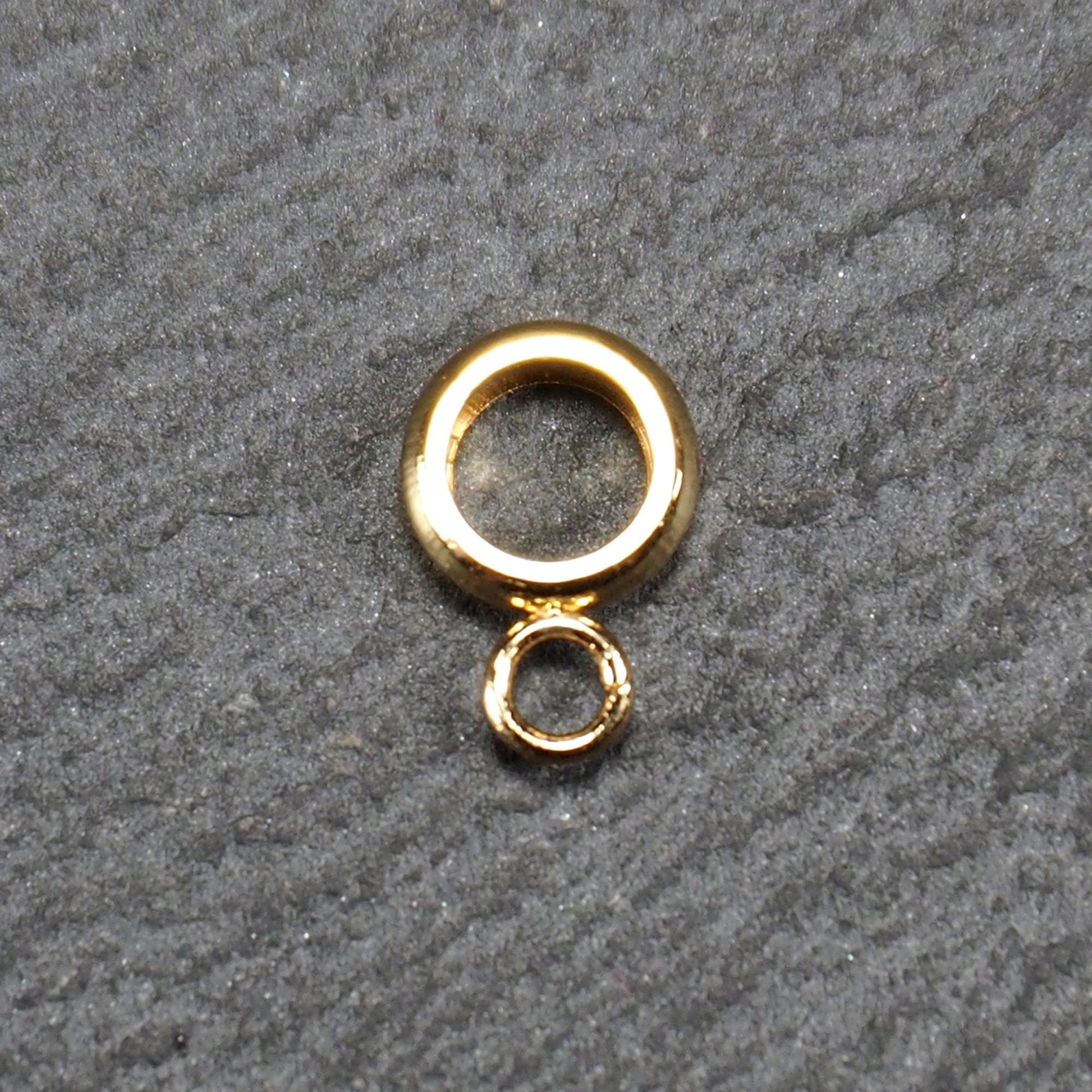 Ringförmige, glänzend goldfarbene Anhängeröse mit großem runden Loch und kleiner runder Anhängerschlaufe.