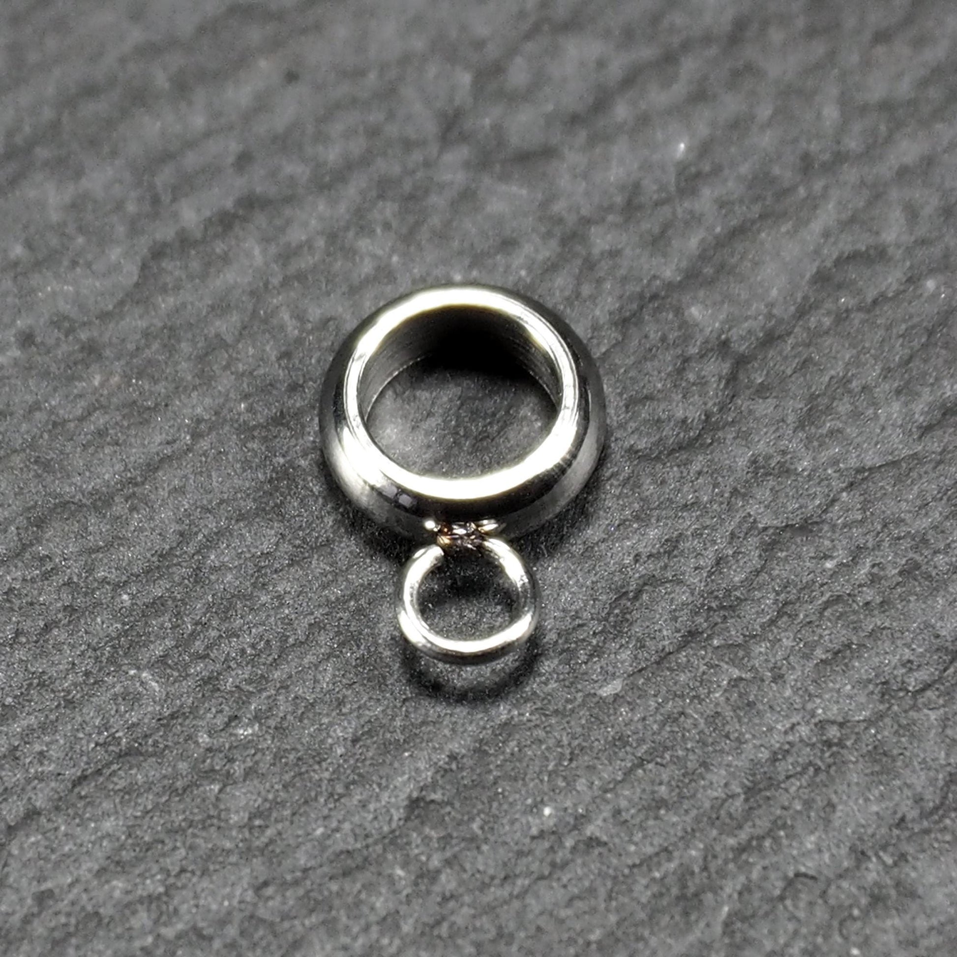 Anhängeröse, silberfarbene glänzende Metallrundung mit zentraler Öffnung und einer kleineren beweglichen Ringöse als Verbindungselement.