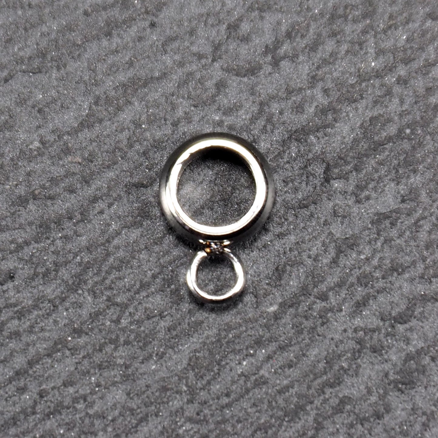 Anhängeröse, silberfarbene glänzende Metallrundung mit zentraler Öffnung und einer kleineren beweglichen Ringöse als Verbindungselement.