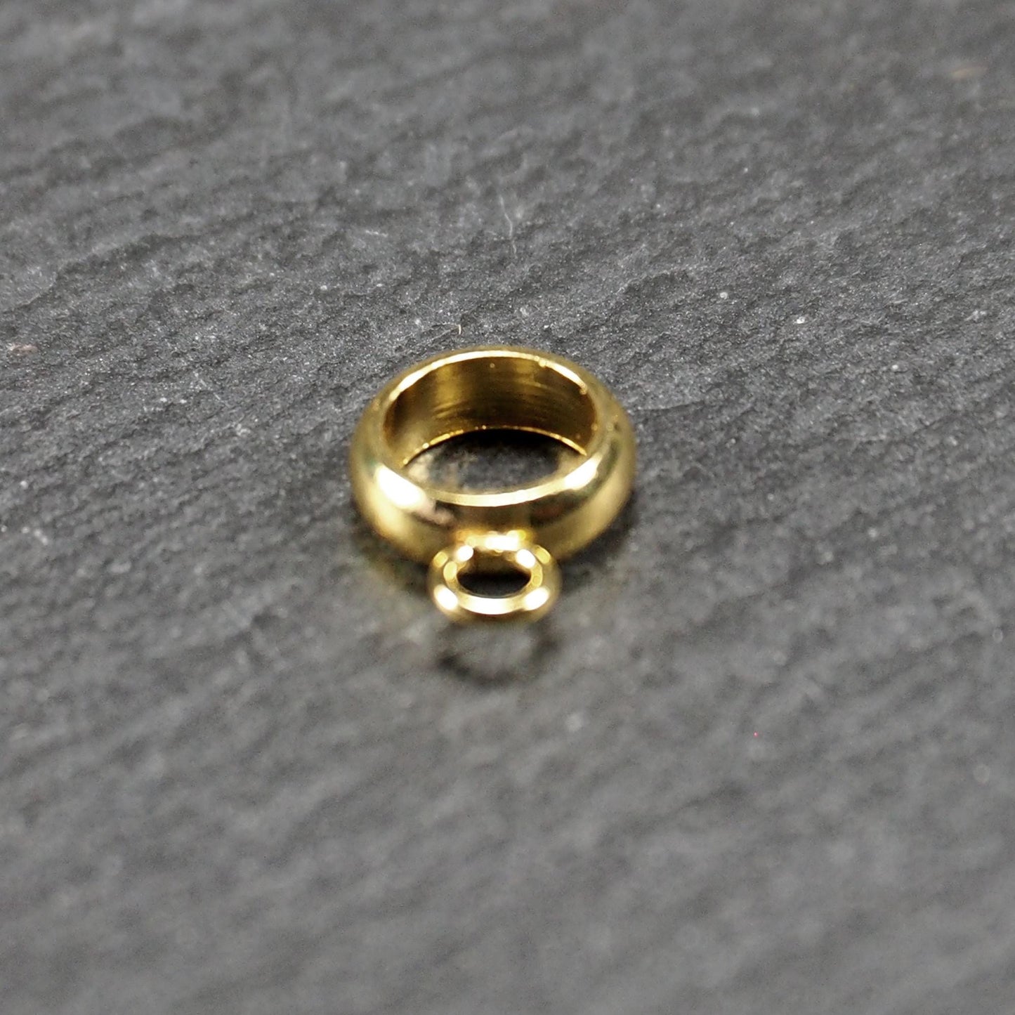 Runde, vergoldete Anhängeröse mit glänzender Oberfläche, offenes Ringdesign und integrierter kleiner Verbindungsöse.