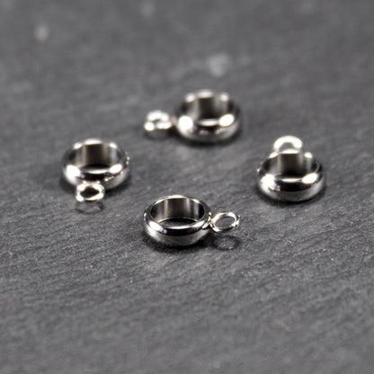 Vier runde, silberfarbene Anhängerösen mit glänzender Oberfläche: hohle Ringscheiben mit jeweils einer kleinen Öse.