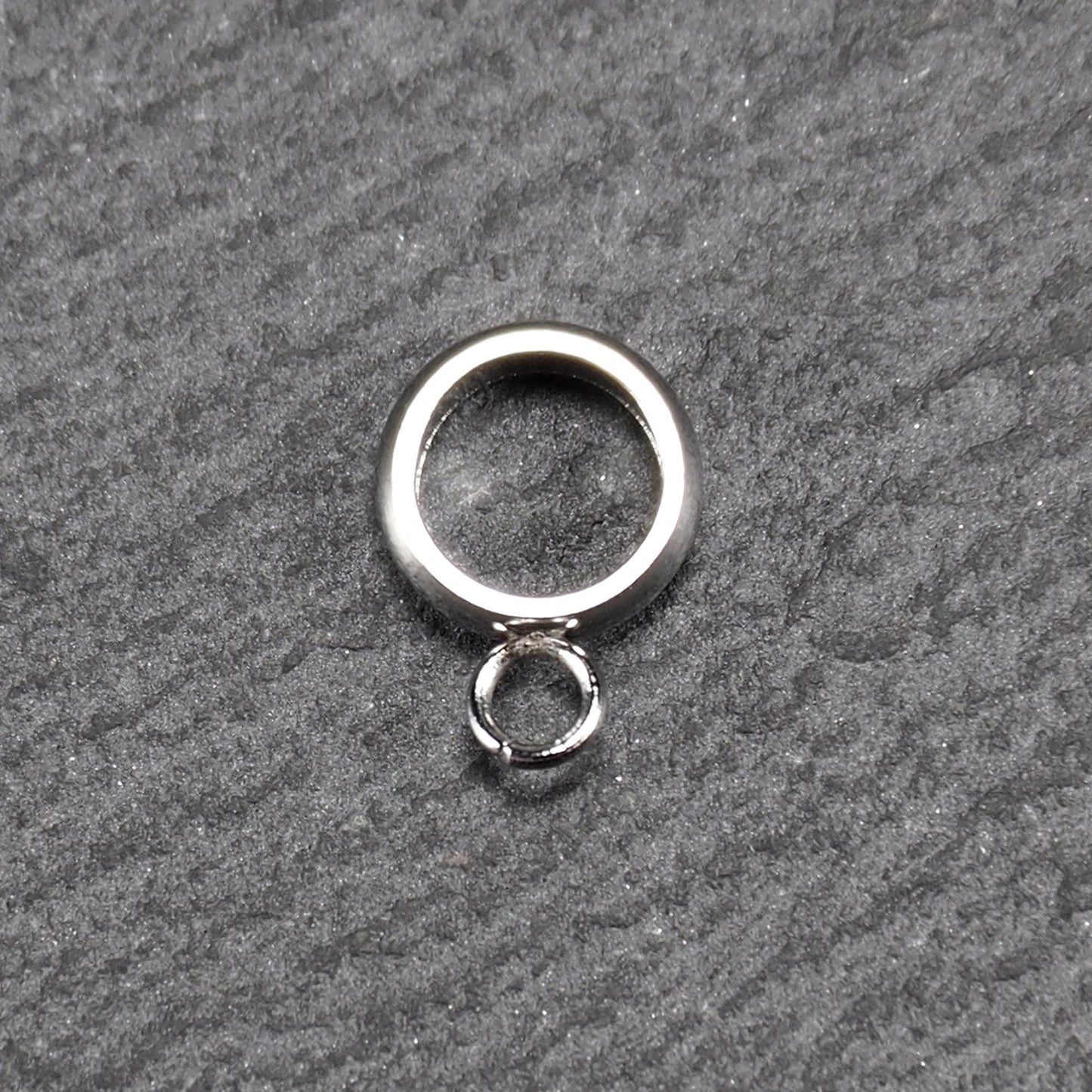 Runder, poliert glänzender silberfarbener Anhängerring mit großem Innenkreis und einer kleineren, unten befestigten Öse.