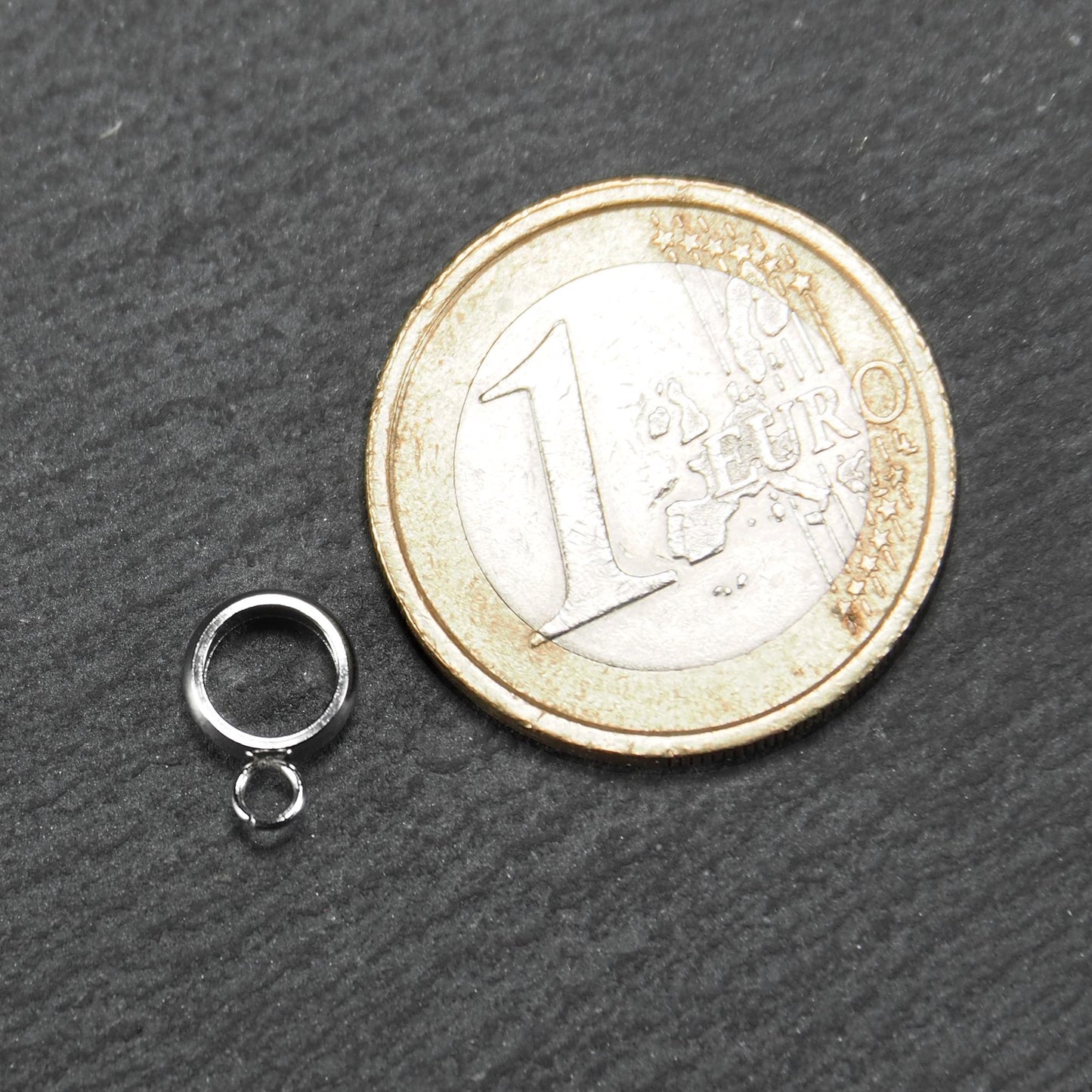 Runde, silberfarbene Anhängeröse mit glänzender Oberfläche und kleinem angehängtem Ösenring, neben einer 1-Euro-Münze.