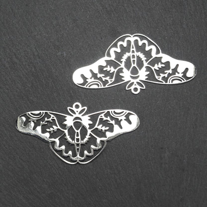 Anhänger / Verbinder in Mottenform aus poliertem silberfarbenem Edelstahl, filigranes durchbrochenes Ornament-Flügeldesign mit integrierter Öse oben.