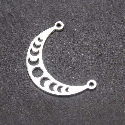Sichelförmiger silberner Metallverbinder mit ausgeschnittenem Mondphasen-Motiv und je einer Rundöse an den Enden.