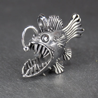 3D-Anhänger Anglerfisch, silberglänzend, mit geöffnetem Maul und dolchartigen Zähnen, geriffelten Flossen, punktiertem Körper und Öse.