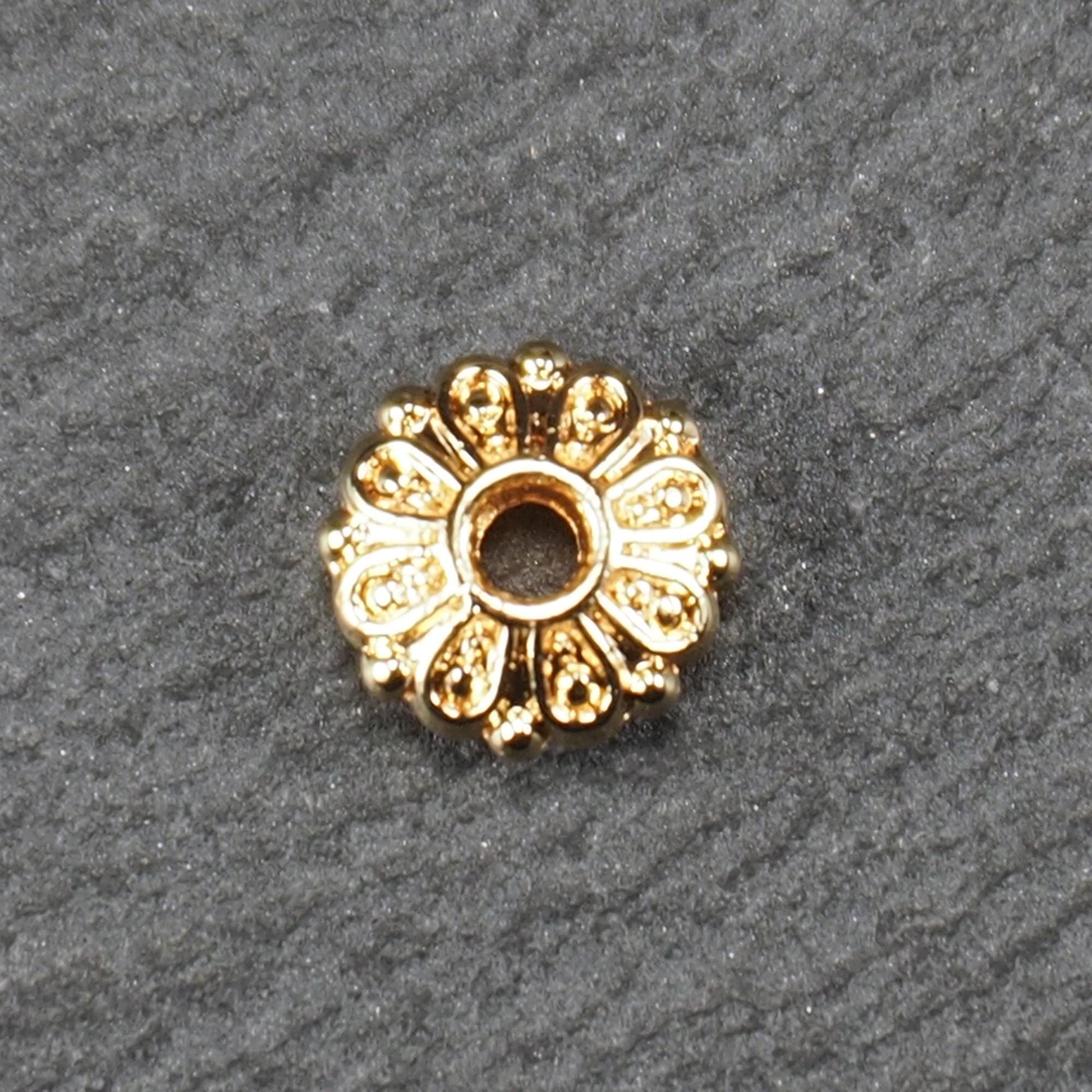 Runde, goldfarbene Scheiben-Spacer-Perle mit mittigem Loch und reliefierter, blütenartiger radialer Ornamentgravur.