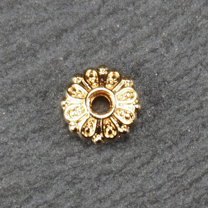 Runde, goldfarbene Scheiben-Spacer-Perle mit mittigem Loch und reliefierter, blütenartiger radialer Ornamentgravur.