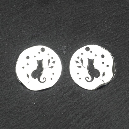 Runder, flacher Anhänger aus poliertem Edelstahl, Cut-out mit sitzender Katzen-Silhouette und Blattzweig, Öse oben und mehrere kleine Bohrungen.