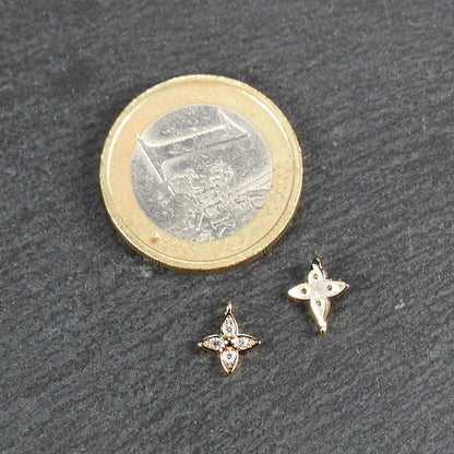 Vierblättriger goldfarbener Anhänger mit vier eingelassenen klaren Steinchen und zentraler Kugel, Öse sichtbar; daneben 1‑Euro‑Münze.