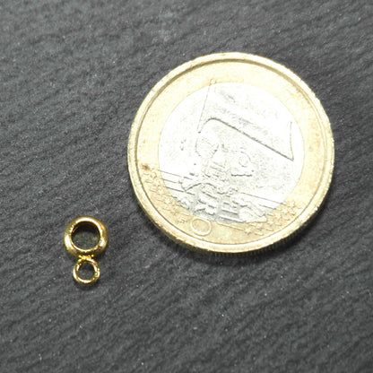 Anhängeröse, goldfarben und glänzend, ringförmig mit zusätzlicher kleiner Öse, neben einer 1‑Euro‑Münze zur Größendarstellung.