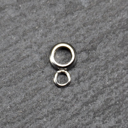 Runde Anhängeröse mit silberglänzender Oberfläche, kompakter durchbrochener Ring mit kleinem geschlossenen Ring unten.