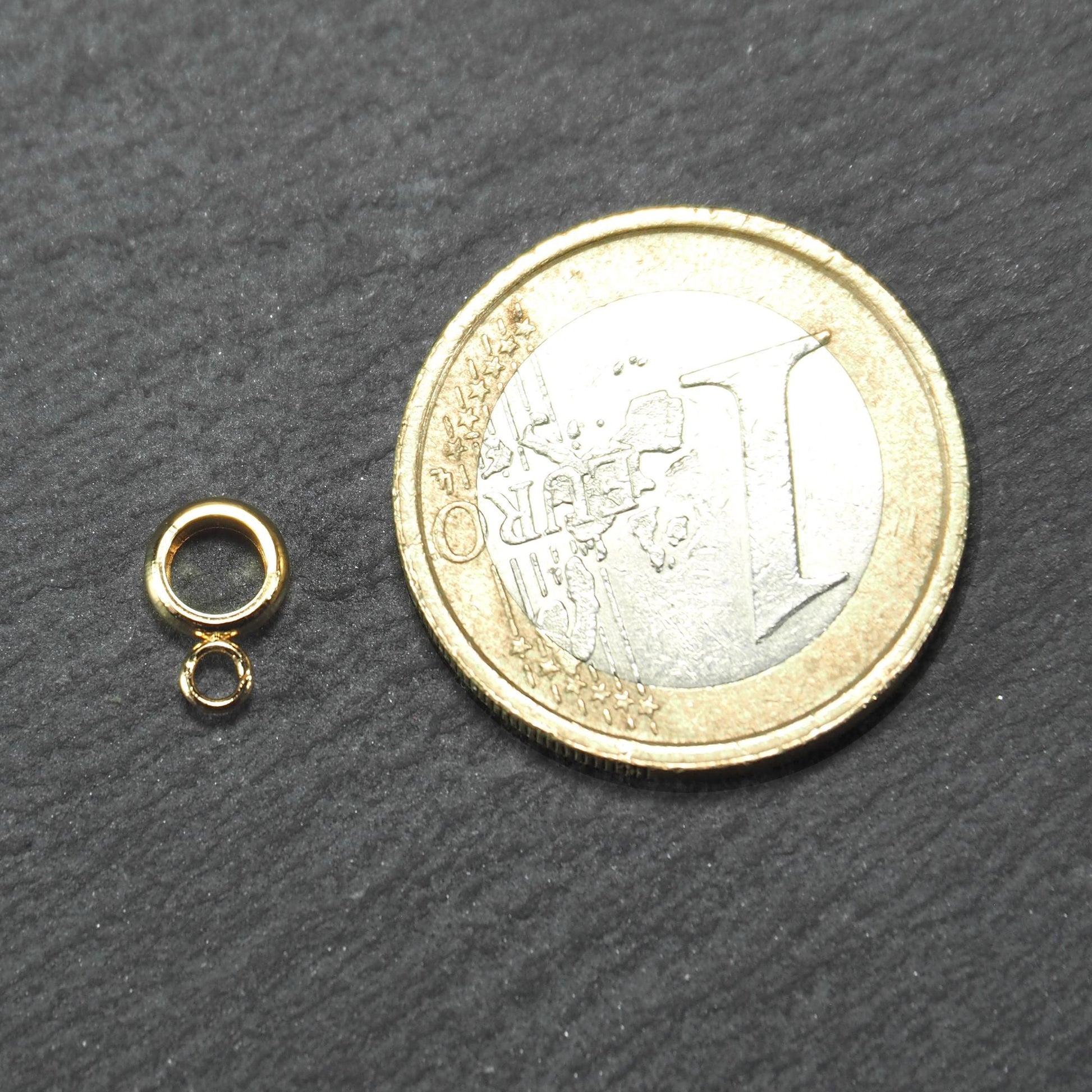 Ringförmige goldfarbene Anhängeröse mit kleiner offener Öse und glatter glänzender Oberfläche neben 1‑Euro‑Münze als Größenbezug.