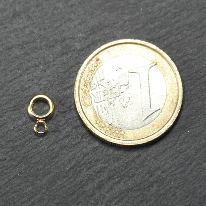 Ringförmige goldfarbene Anhängeröse mit kleiner offener Öse und glatter glänzender Oberfläche neben 1‑Euro‑Münze als Größenbezug.