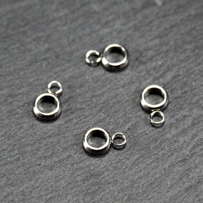 Vier glänzende silberfarbene runde Anhängerösen, jeweils ein größerer hohler Ring mit einer kleineren beweglichen Ringöse.