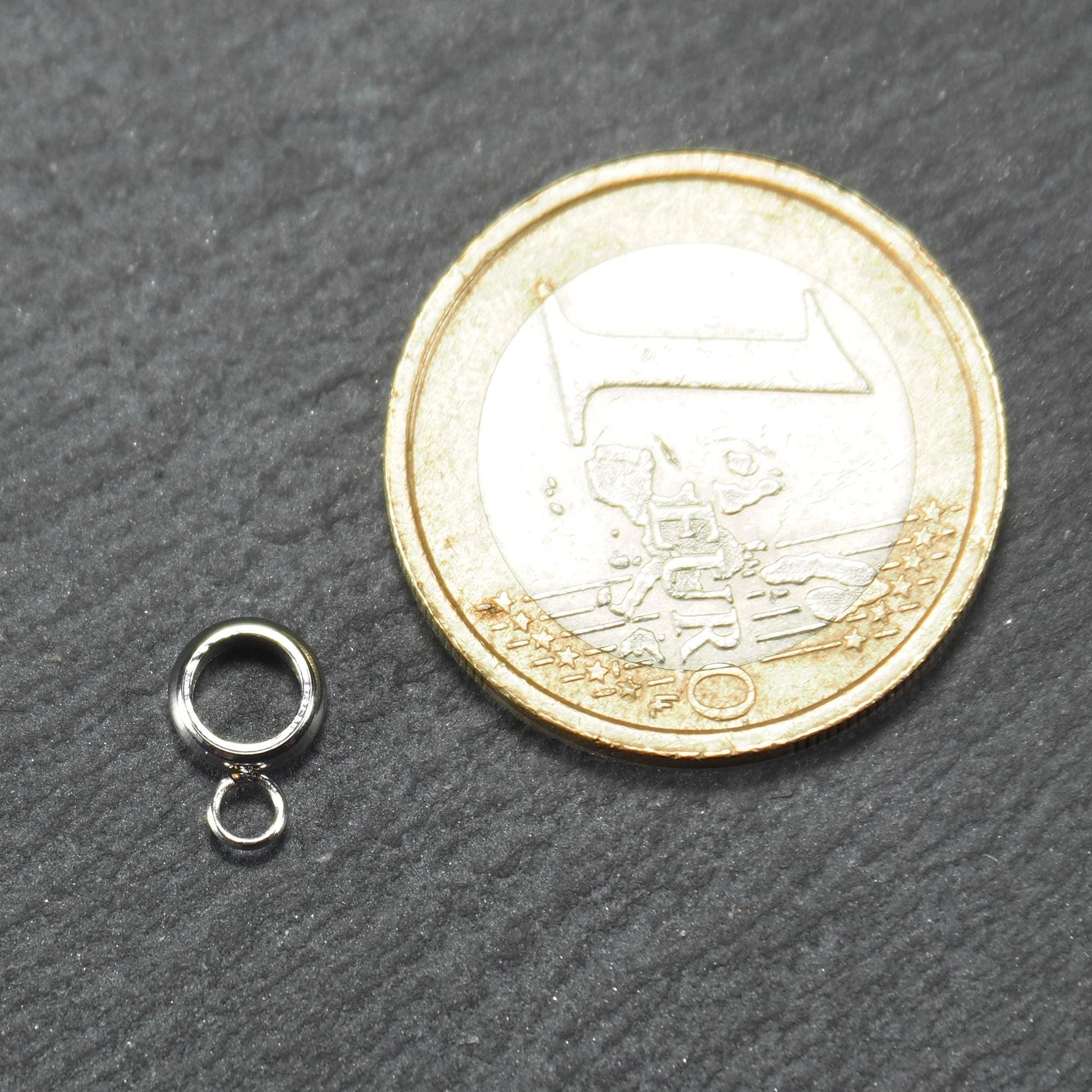 Runde silberfarbene glänzende Anhängeröse mit zusätzlicher kleiner Ringöse, neben einer 1-Euro-Münze zur Größenangabe.