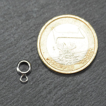 Runde silberfarbene glänzende Anhängeröse mit zusätzlicher kleiner Ringöse, neben einer 1-Euro-Münze zur Größenangabe.