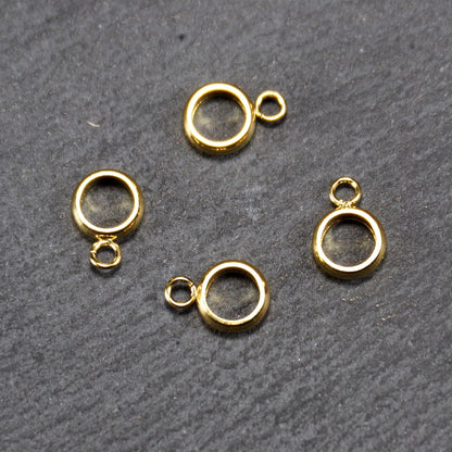 Vier runde, goldfarbene glänzende Anhängerösen in Ringform mit durchbrochenem Innenraum und integrierter kleiner Öse.
