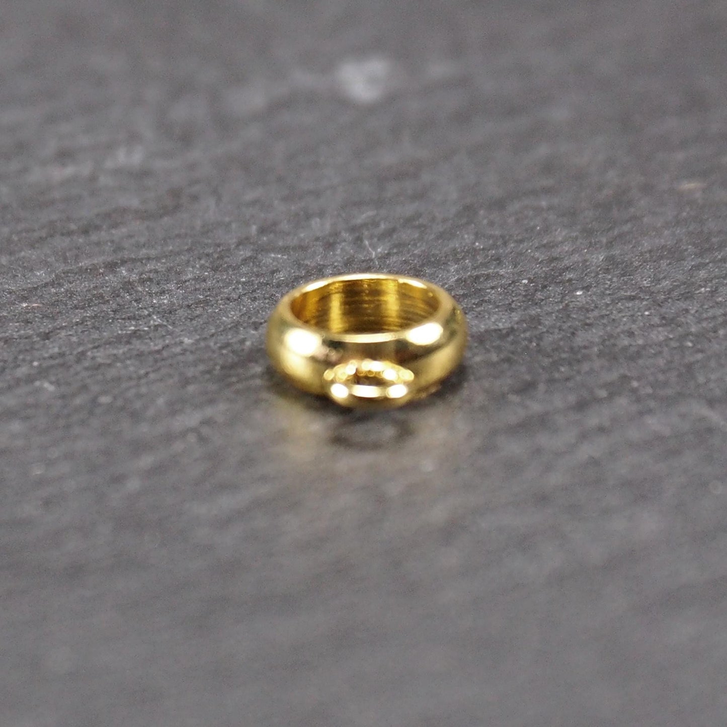 Runde, vergoldete Anhängeröse mit glänzender Oberfläche, offenes Ringdesign und integrierter kleiner Verbindungsöse.