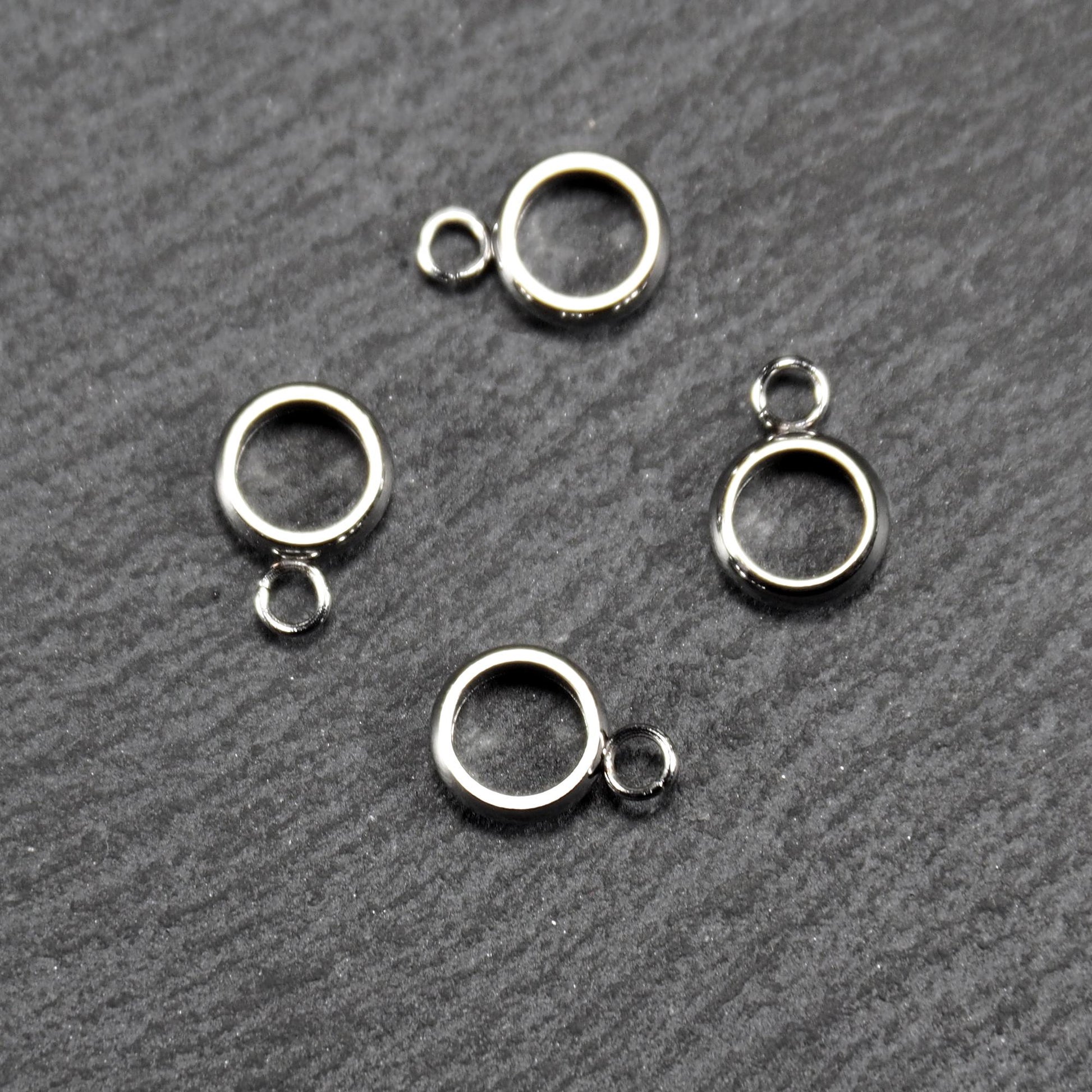 Vier runde, silberfarbene Anhängerösen mit glänzender Oberfläche: hohle Ringscheiben mit jeweils einer kleinen Öse.