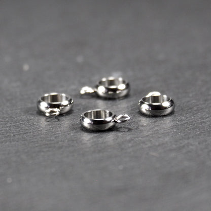 Vier runde, silberfarbene Anhängerösen mit glänzender Oberfläche: hohle Ringscheiben mit jeweils einer kleinen Öse.