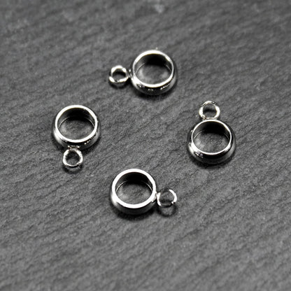 Vier runde, silberfarbene Anhängerösen mit glänzender Oberfläche: hohle Ringscheiben mit jeweils einer kleinen Öse.