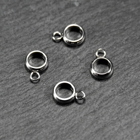 Vier runde, silberfarbene Anhängerösen mit glänzender Oberfläche: hohle Ringscheiben mit jeweils einer kleinen Öse.