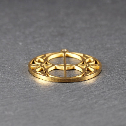 Runder, goldfarbener, filigran durchbrochener Anhänger mit symmetrischem Vesica-Piscis-Ornament und kleiner Öse oben.