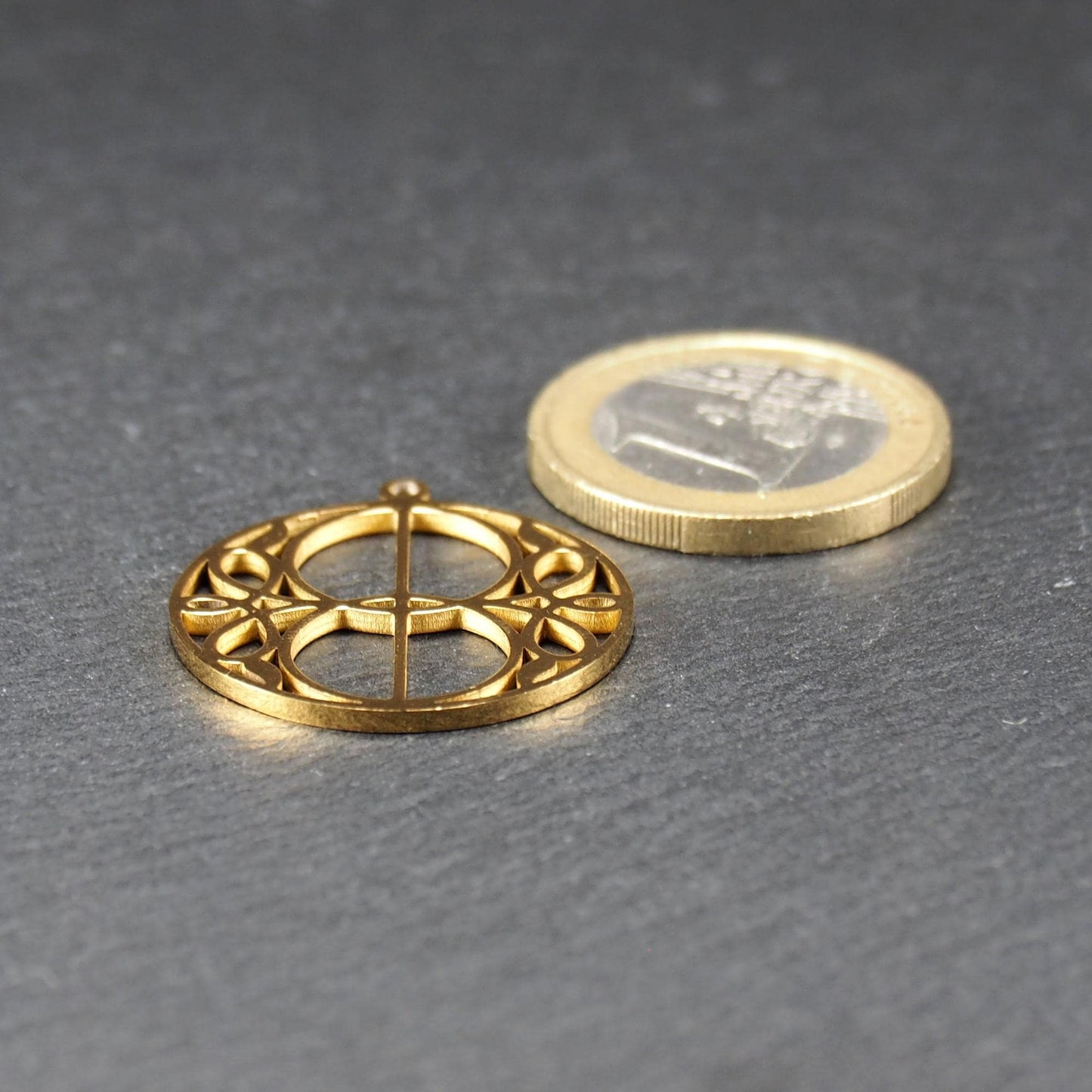 Runder, goldfarbener, filigran durchbrochener Anhänger mit symmetrischem Vesica-Piscis-Ornament und kleiner Öse oben.