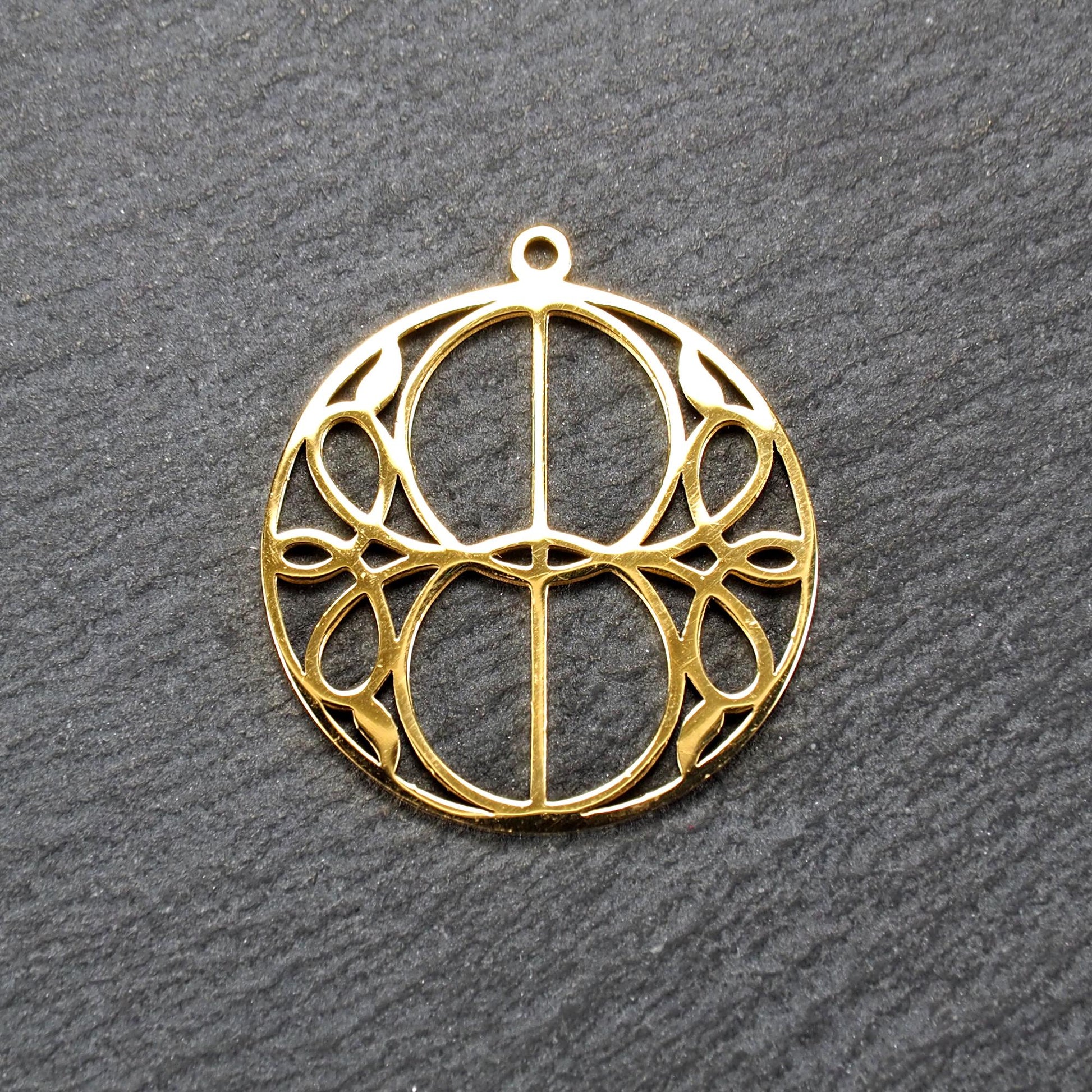 Runder, goldfarbener, filigran durchbrochener Anhänger mit symmetrischem Vesica-Piscis-Ornament und kleiner Öse oben.