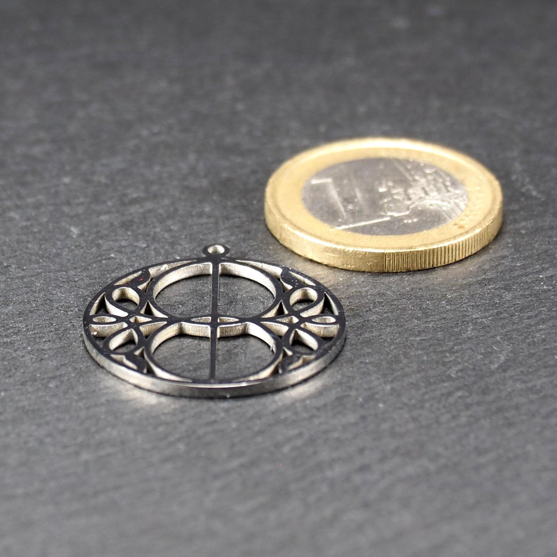 Runder, silberfarbener, polierter Anhänger mit filigranem, durchbrochenem Vesica-Piscis-/Mandorla-Motiv und integrierter Öse oben.