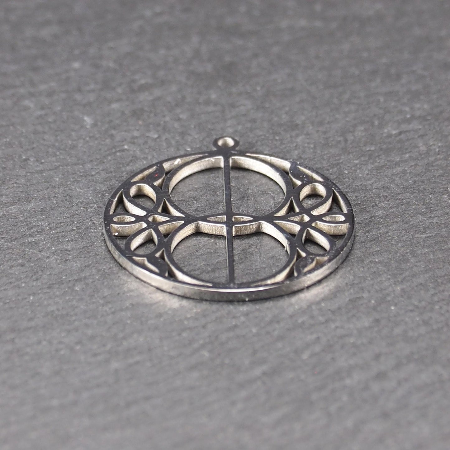 Runder, silberfarbener, polierter Anhänger mit filigranem, durchbrochenem Vesica-Piscis-/Mandorla-Motiv und integrierter Öse oben.