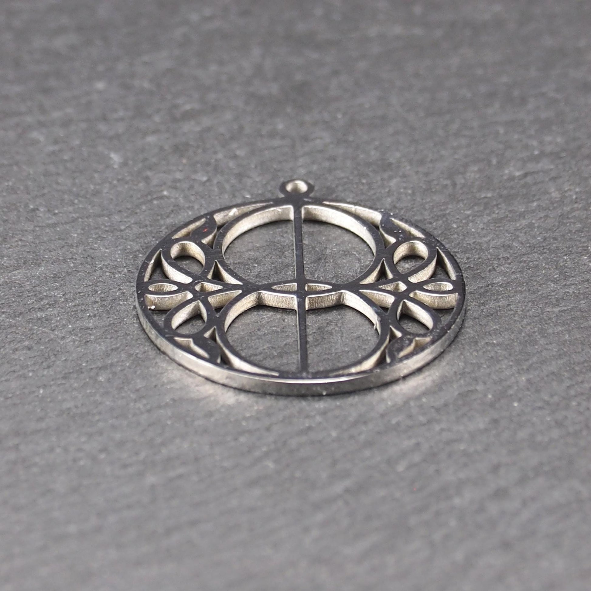 Runder, silberfarbener, polierter Anhänger mit filigranem, durchbrochenem Vesica-Piscis-/Mandorla-Motiv und integrierter Öse oben.