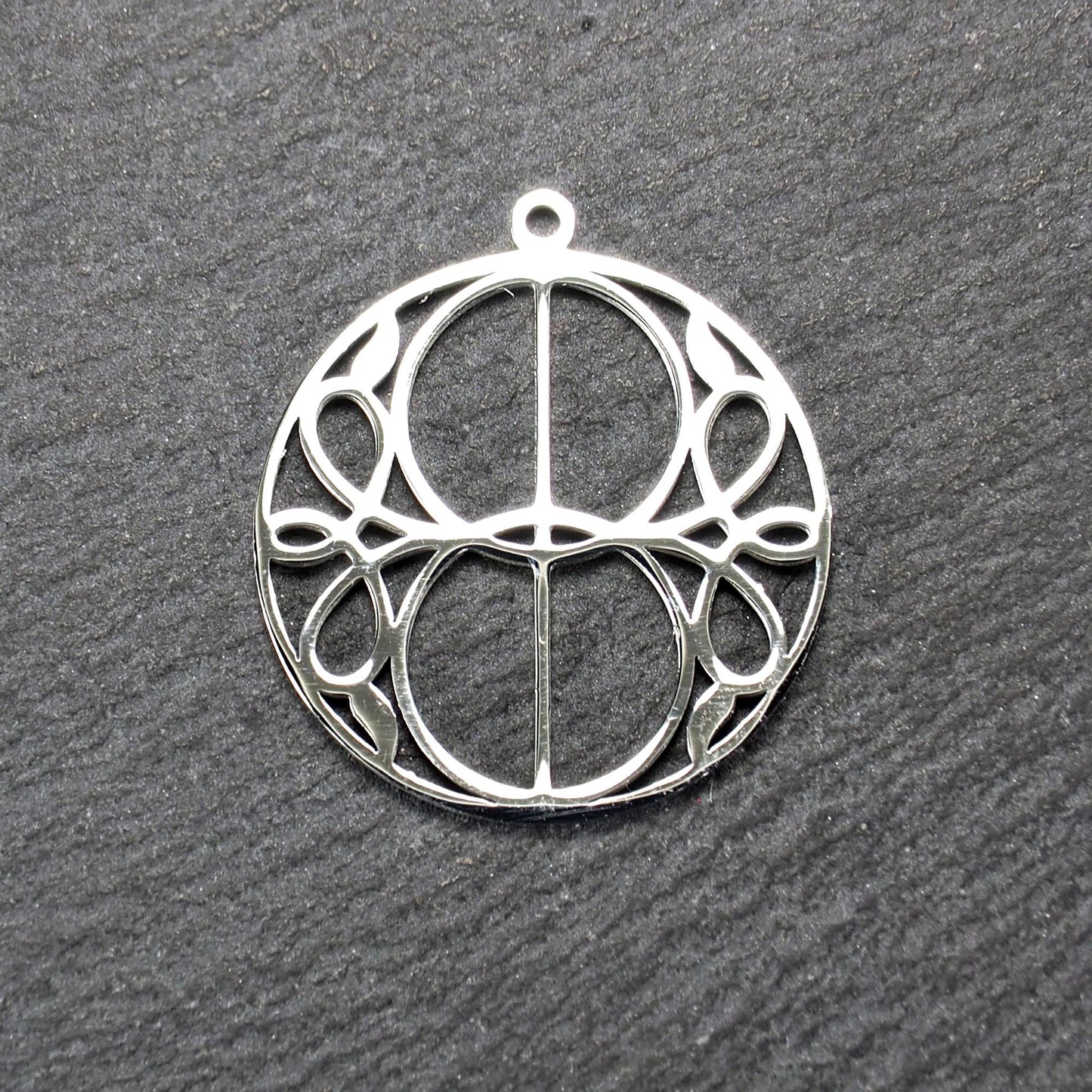 Runder, silberfarbener, polierter Anhänger mit filigranem, durchbrochenem Vesica-Piscis-/Mandorla-Motiv und integrierter Öse oben.
