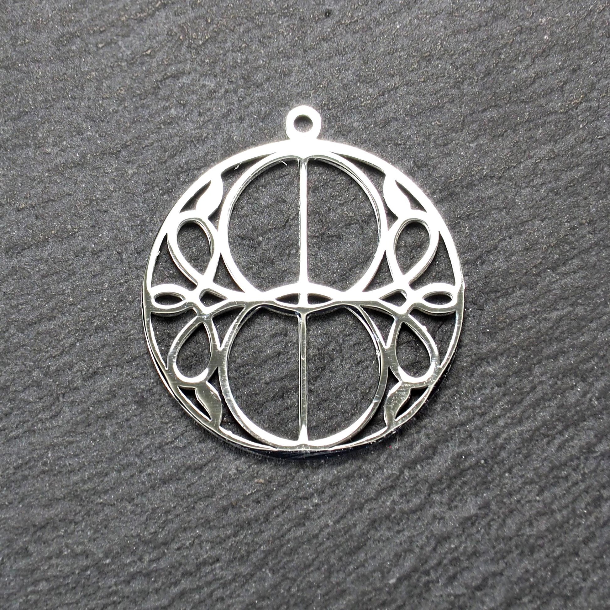 Runder, silberfarbener, polierter Anhänger mit filigranem, durchbrochenem Vesica-Piscis-/Mandorla-Motiv und integrierter Öse oben.