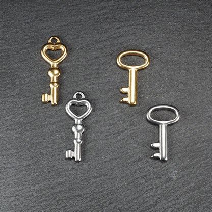 Vier glänzende Schlüsselanhänger, zwei vergoldet und zwei silberfarben; zwei mit herzförmiger Öse, zwei mit ovaler Öse.