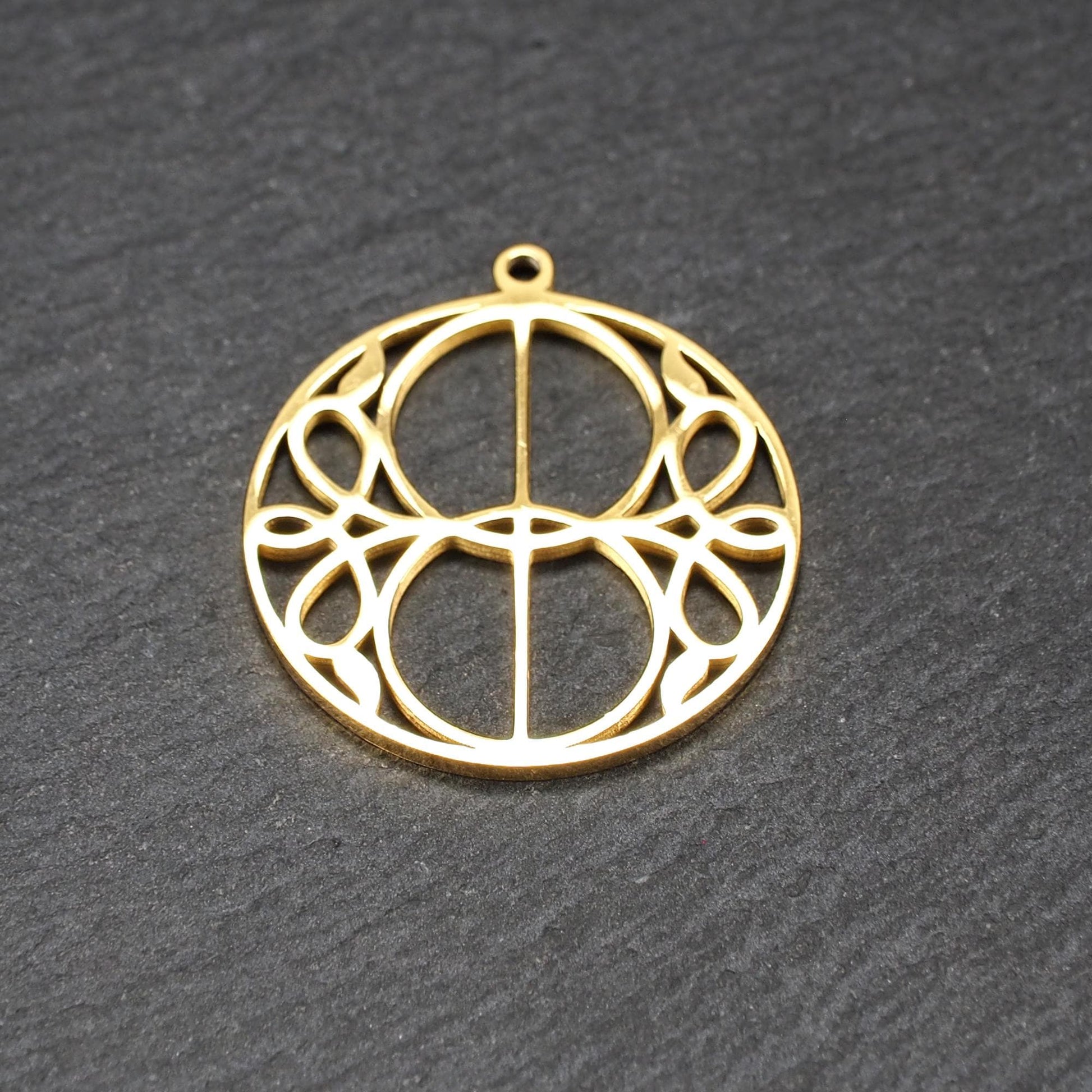Runder, goldfarbener, filigran durchbrochener Anhänger mit symmetrischem Vesica-Piscis-Ornament und kleiner Öse oben.