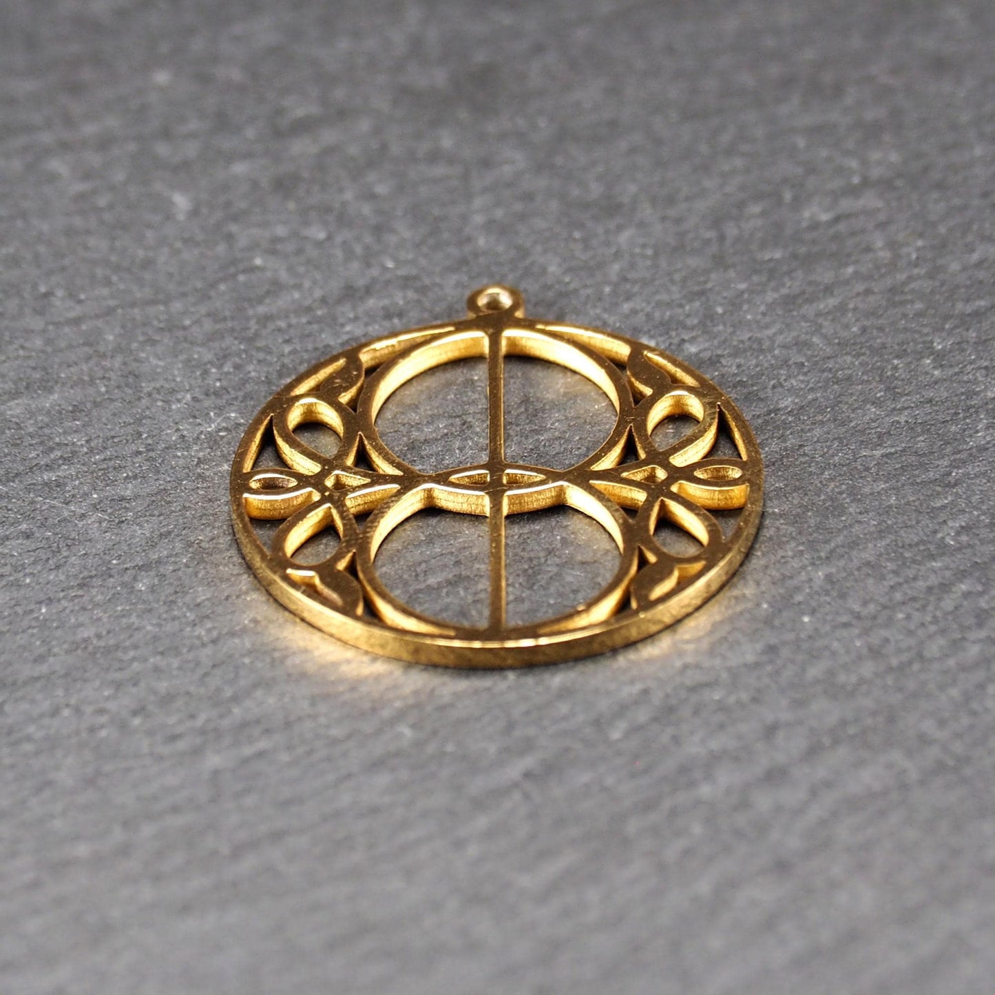 Runder, goldfarbener, filigran durchbrochener Anhänger mit symmetrischem Vesica-Piscis-Ornament und kleiner Öse oben.