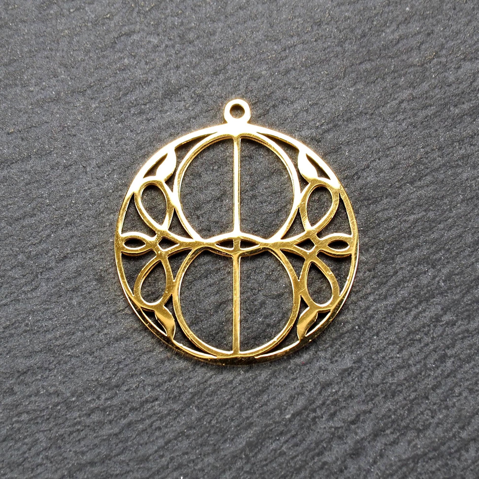 Runder, goldfarbener, filigran durchbrochener Anhänger mit symmetrischem Vesica-Piscis-Ornament und kleiner Öse oben.