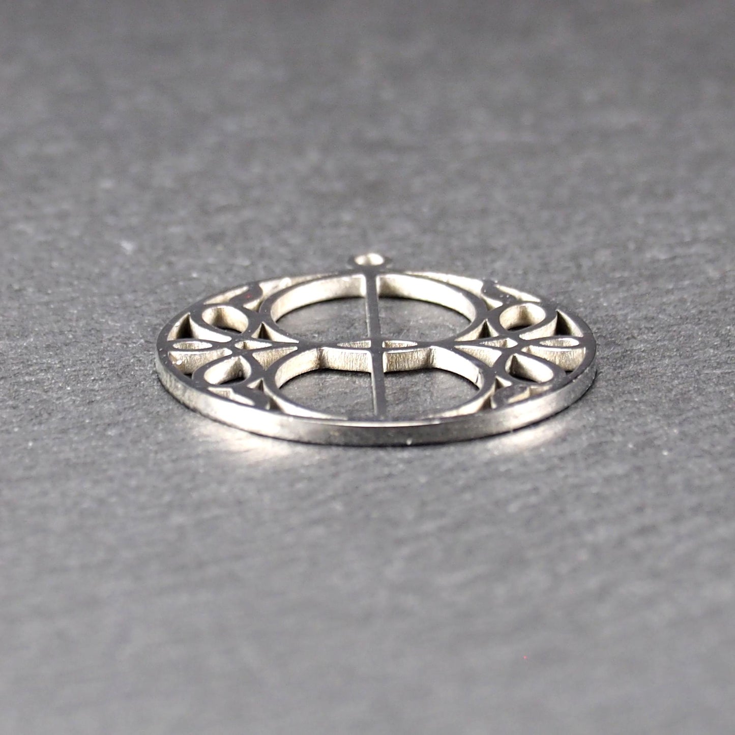 Runder, silberfarbener, polierter Anhänger mit filigranem, durchbrochenem Vesica-Piscis-/Mandorla-Motiv und integrierter Öse oben.