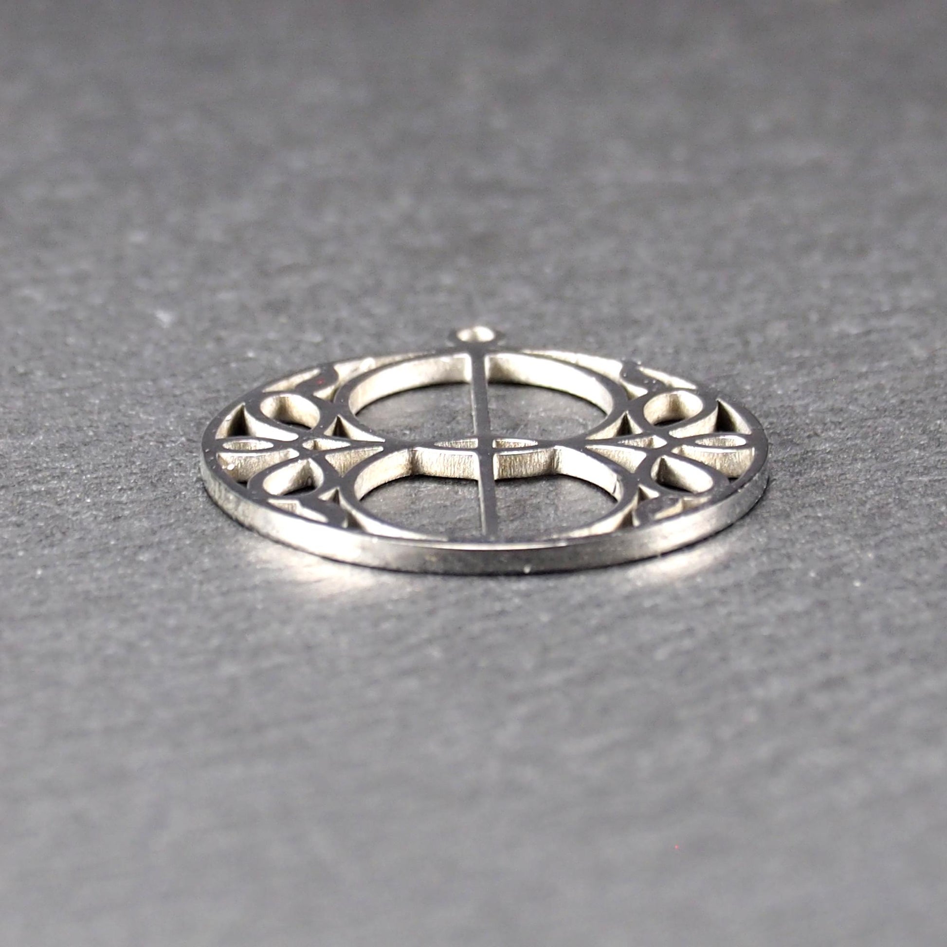 Runder, silberfarbener, polierter Anhänger mit filigranem, durchbrochenem Vesica-Piscis-/Mandorla-Motiv und integrierter Öse oben.