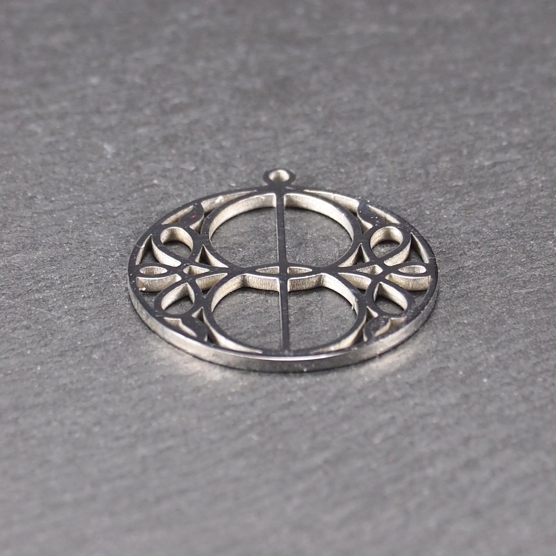 Runder, silberfarbener, polierter Anhänger mit filigranem, durchbrochenem Vesica-Piscis-/Mandorla-Motiv und integrierter Öse oben.