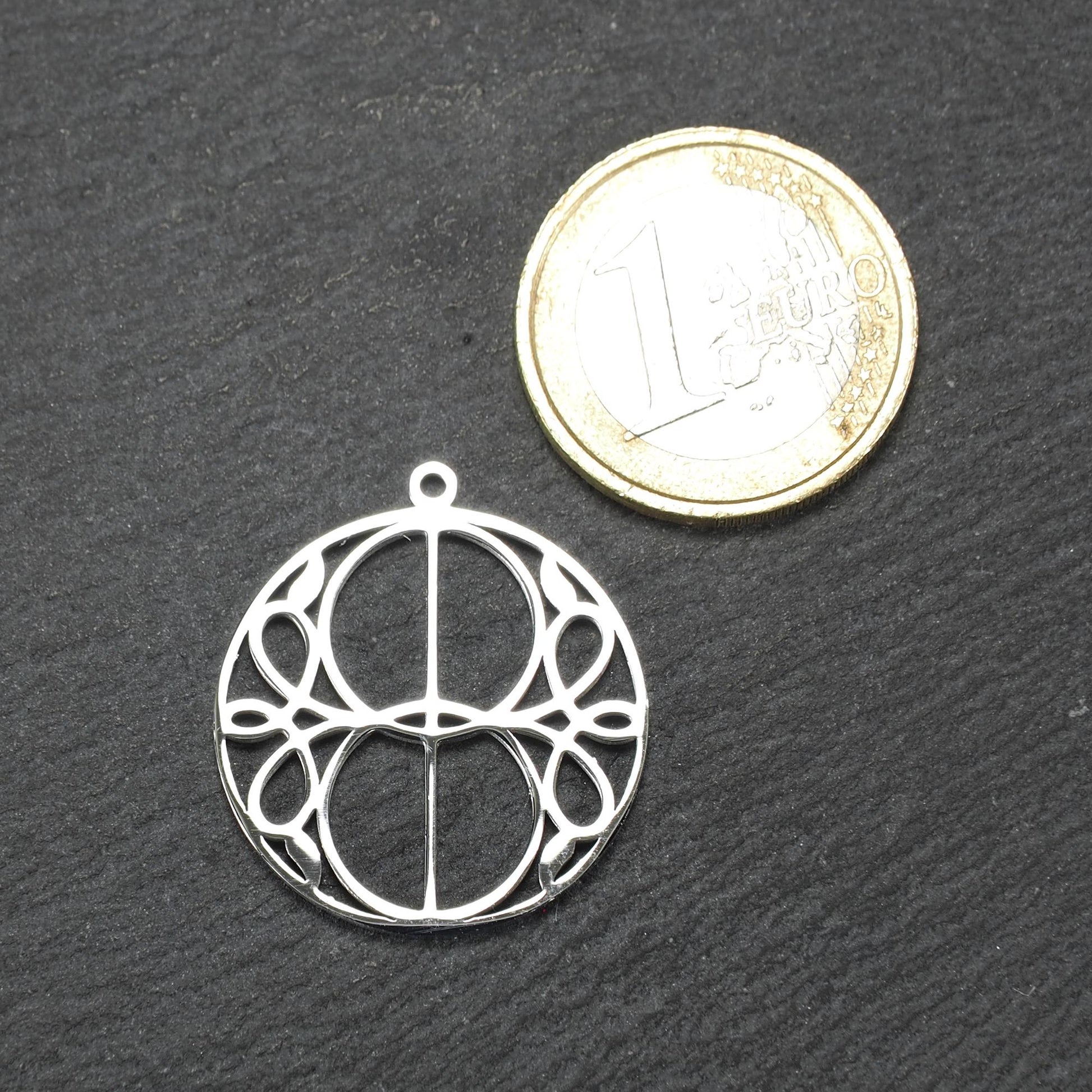 Runder, silberfarbener, polierter Anhänger mit filigranem, durchbrochenem Vesica-Piscis-/Mandorla-Motiv und integrierter Öse oben.