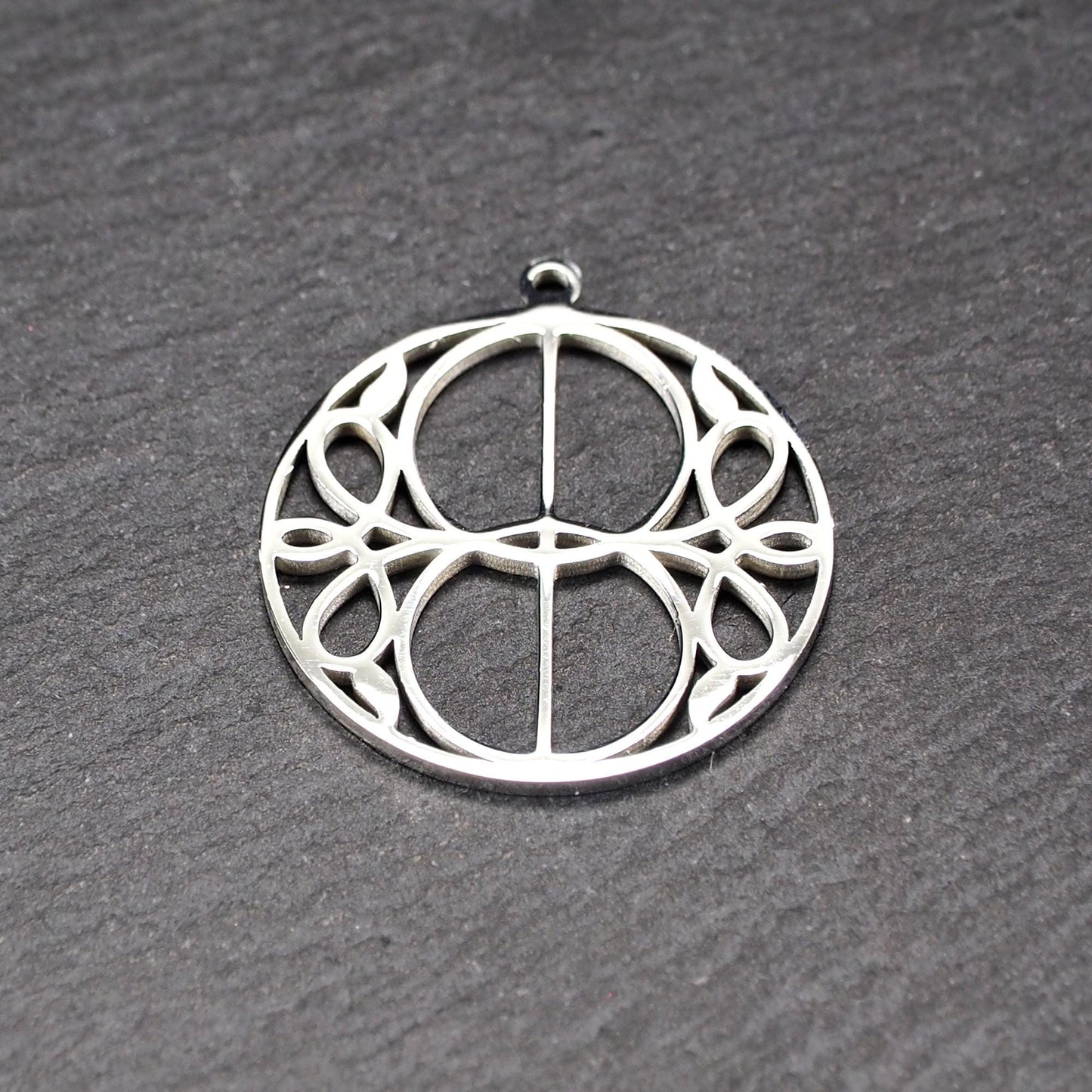 Runder, silberfarbener, polierter Anhänger mit filigranem, durchbrochenem Vesica-Piscis-/Mandorla-Motiv und integrierter Öse oben.
