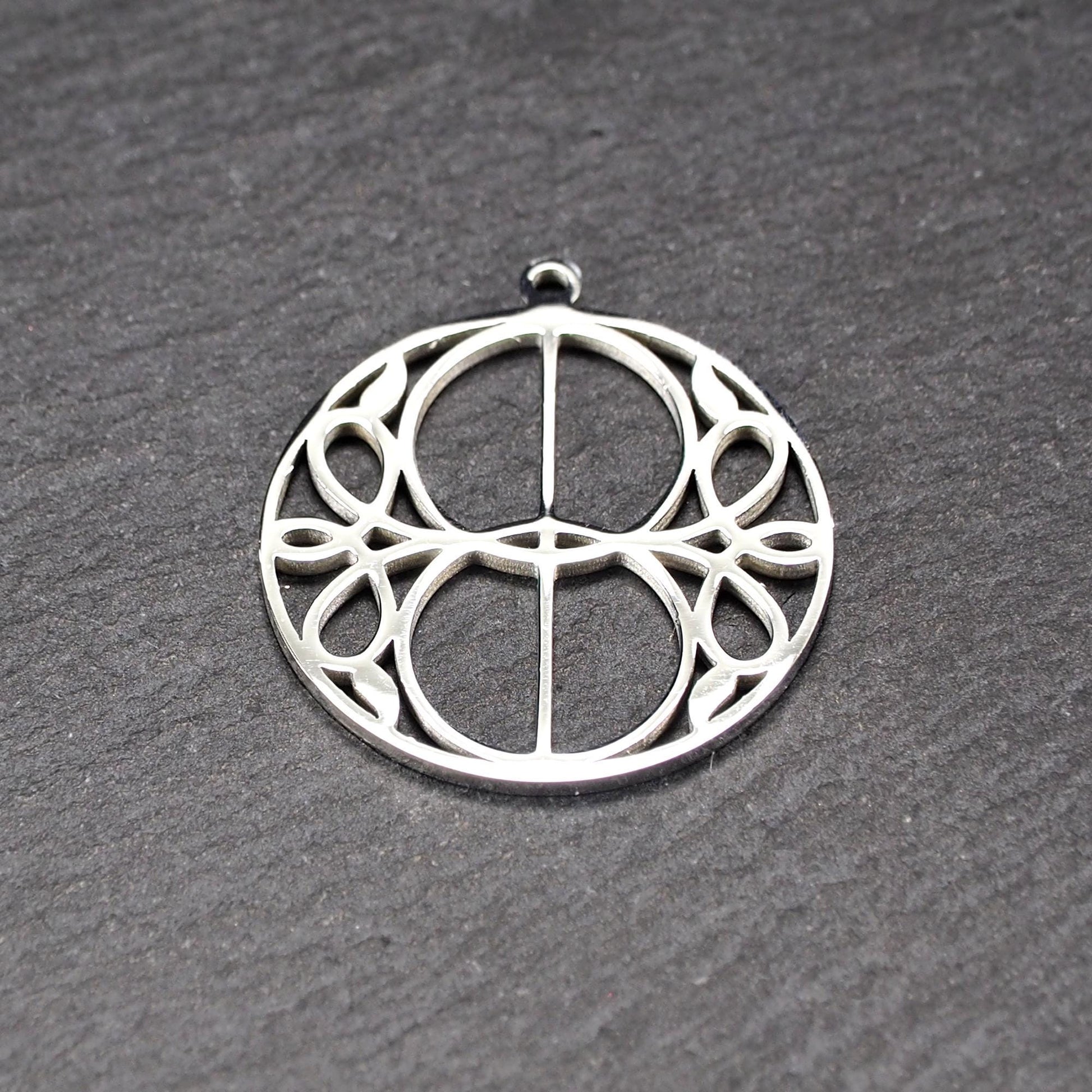Runder, silberfarbener, polierter Anhänger mit filigranem, durchbrochenem Vesica-Piscis-/Mandorla-Motiv und integrierter Öse oben.