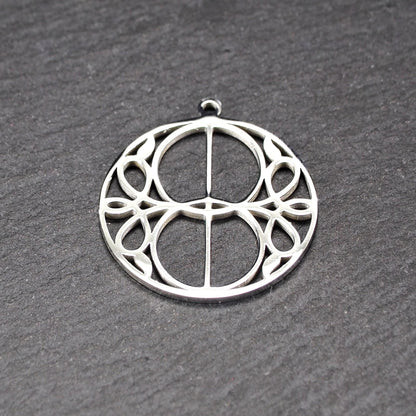 Runder, silberfarbener, polierter Anhänger mit filigranem, durchbrochenem Vesica-Piscis-/Mandorla-Motiv und integrierter Öse oben.