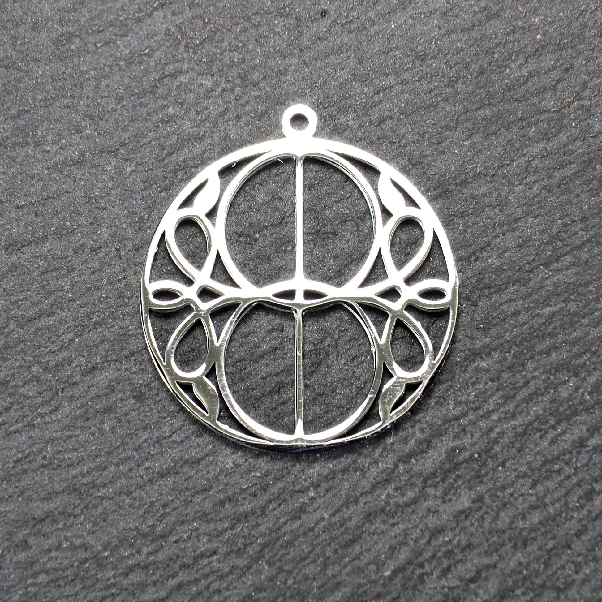 Runder, silberfarbener, polierter Anhänger mit filigranem, durchbrochenem Vesica-Piscis-/Mandorla-Motiv und integrierter Öse oben.