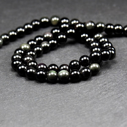 Aufgereihter Perlenstrang aus tiefschwarzen, hochglänzend-polierten, kugelförmigen Obsidianperlen mit glatter Oberfläche.