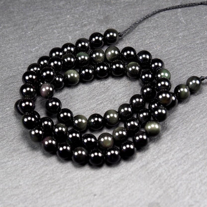 Aufgereihter Perlenstrang aus tiefschwarzen, hochglänzend-polierten, kugelförmigen Obsidianperlen mit glatter Oberfläche.